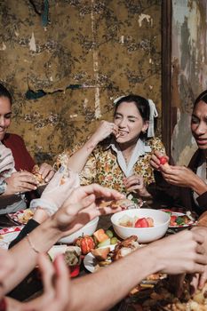 A group of friends enjoying a festive Thanksgiving meal indoors with laughter. - Fotografer Sidoarjo