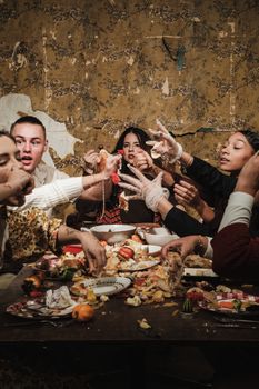 A lively and messy dinner party with friends sharing food and laughter around a table.