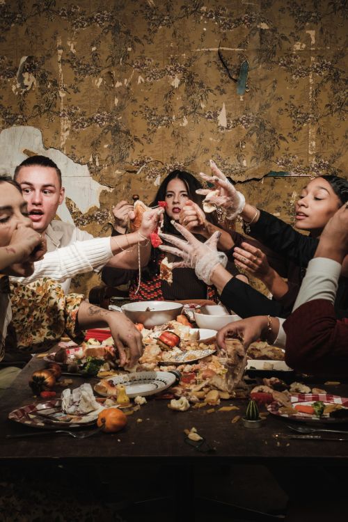 Free A lively and messy dinner party with friends sharing food and laughter around a table. Stock Photo