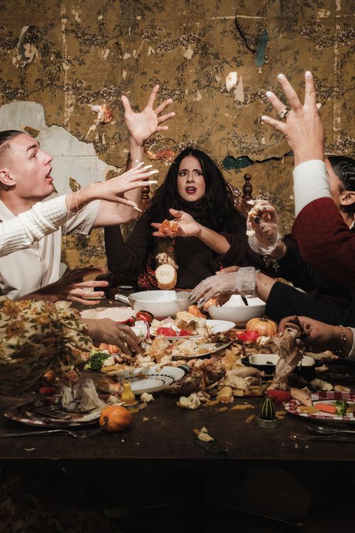 Free A lively scene of people engaging in a food fight around a festive dinner table. Stock Photo