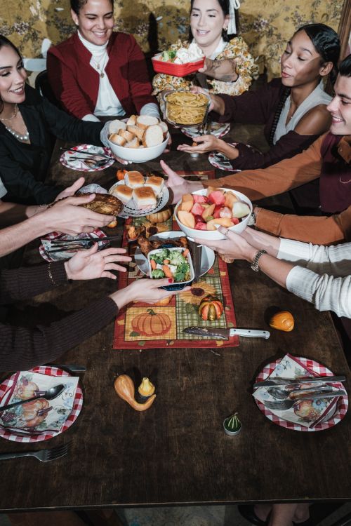 Free People sharing a festive meal around a table, celebrating Thanksgiving with joy and togetherness. Stock Photo