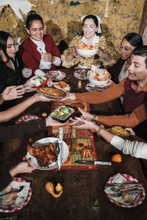 Free A diverse group of friends sharing a festive holiday meal indoors, enjoying a traditional feast. Stock Photo