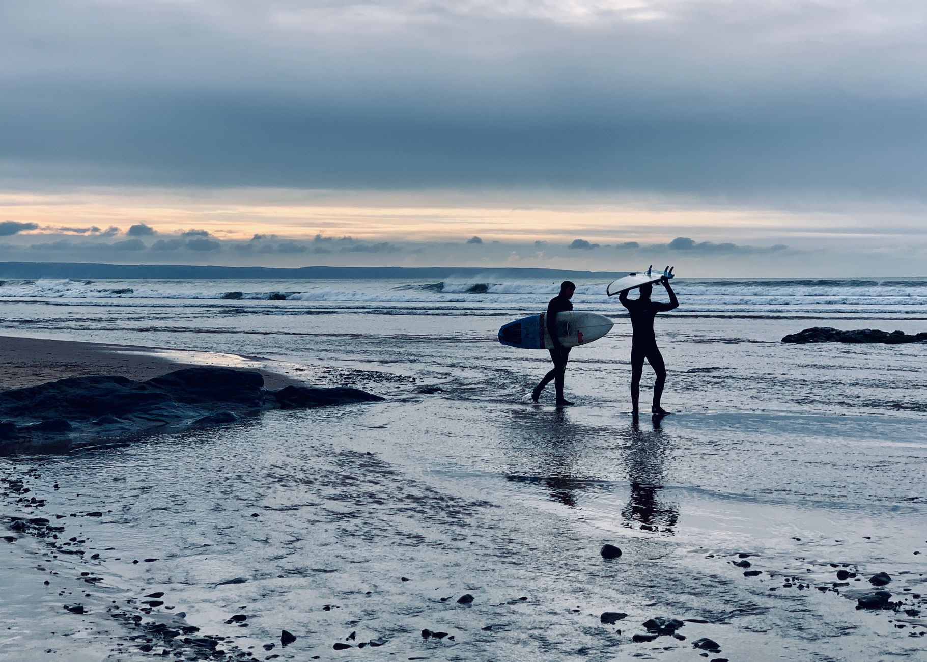 Surfers at sunset on Croyde Beach, North Devon, England