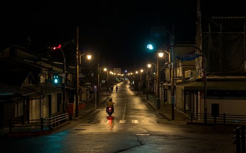 Free A tranquil night scene in Arashiyama, Kyoto, with streetlights and a lone motorbike. Stock Photo