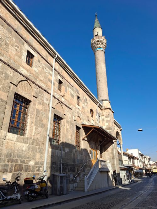 Free Stone-walled mosque with a prominent minaret under clear blue skies in a city setting. Stock Photo