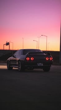 Vintage car with glowing taillights against a vibrant Ankara sunset sky.