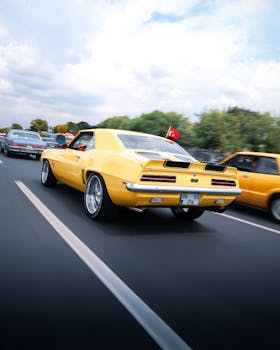 Classic yellow Camaro cruising through Ankara streets under a clear sky.