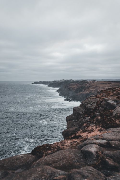 Free Breathtaking view of a rugged cliff coastline under a moody overcast sky. Stock Photo