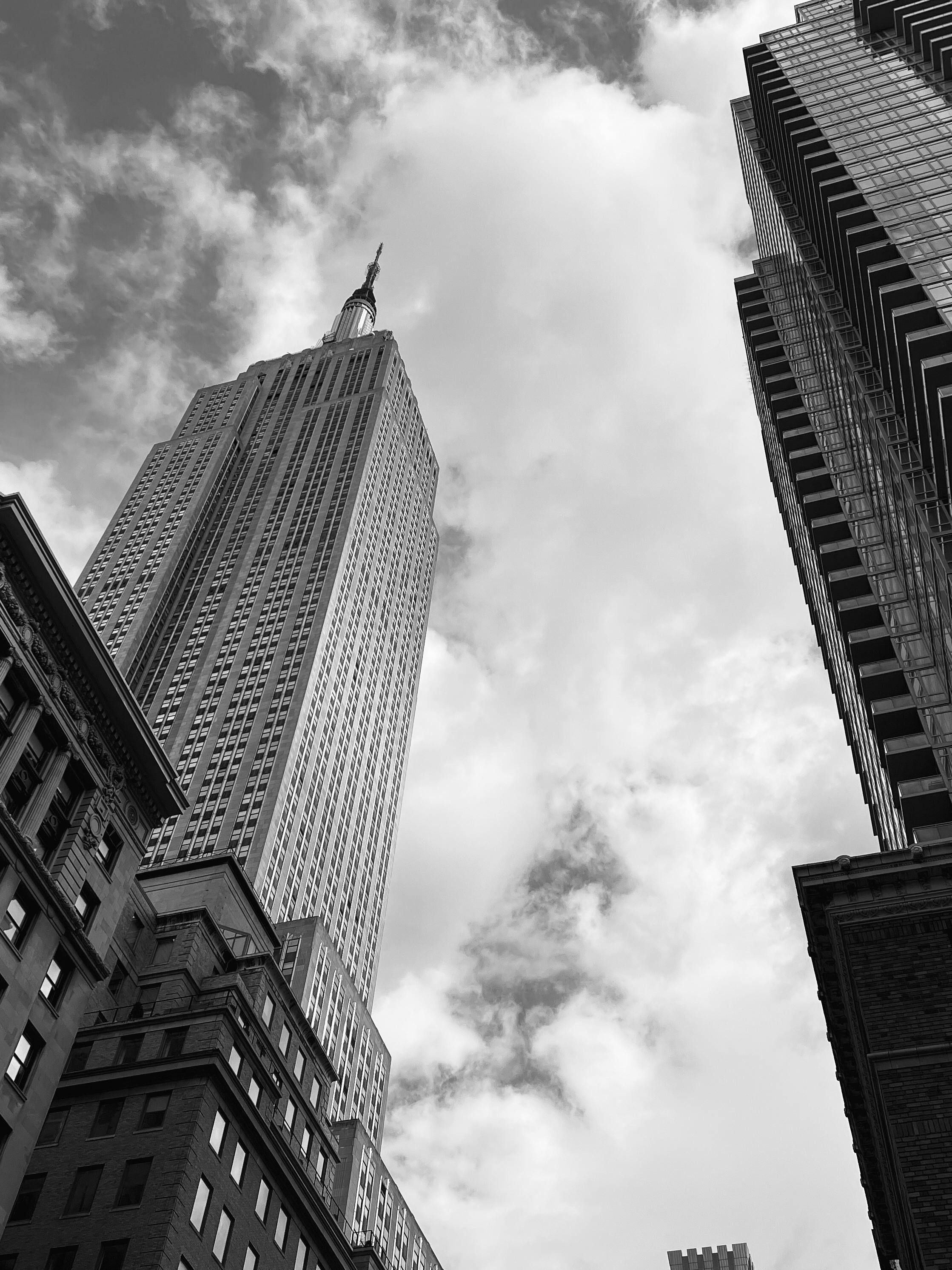Iconic black and white view of the Empire State Building from street level in New York City.
