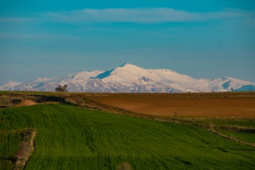 Free Lush green fields with Mount Erciyes in the distance under a clear blue sky. Stock Photo