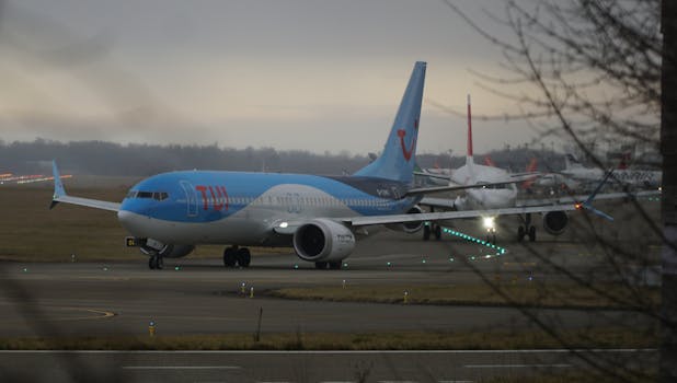 A commercial airplane on the runway at an airport during a cloudy day, ready for takeoff.