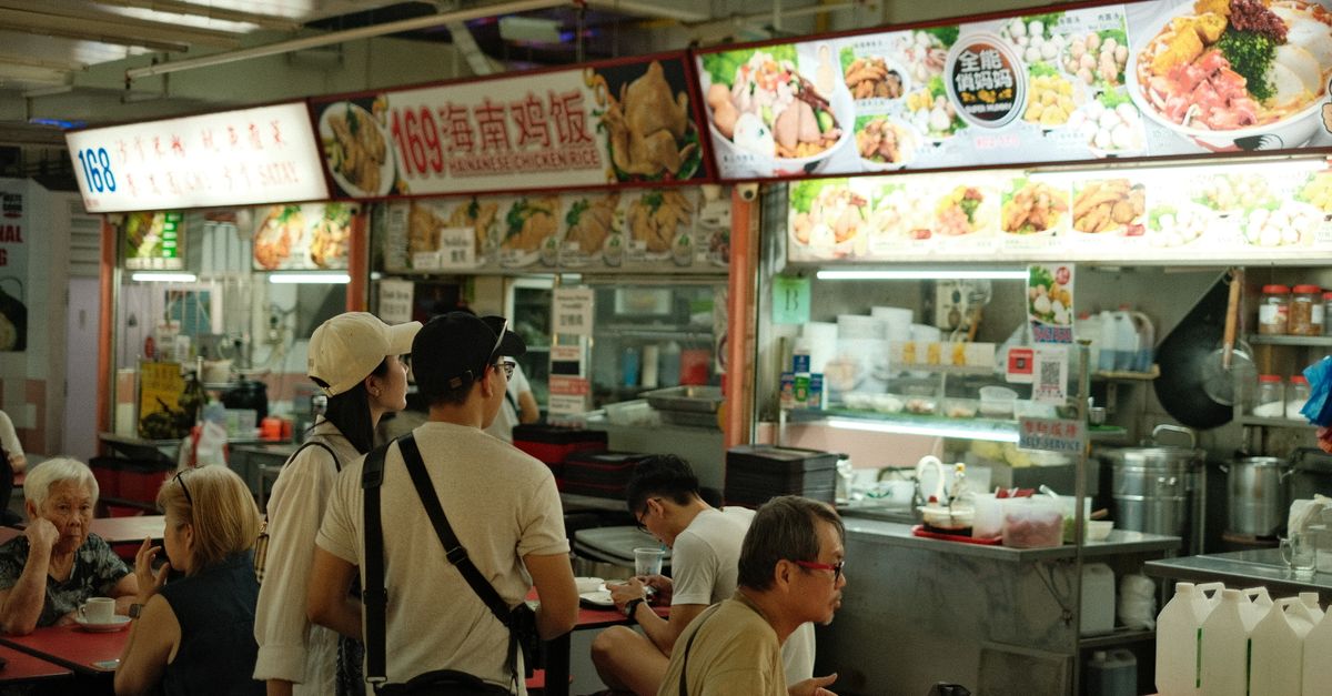 Diners eating at tables in a Singapore hawker centre.