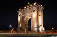 Illuminated Triumphal Arch in Bucharest, Romania, captured at night.