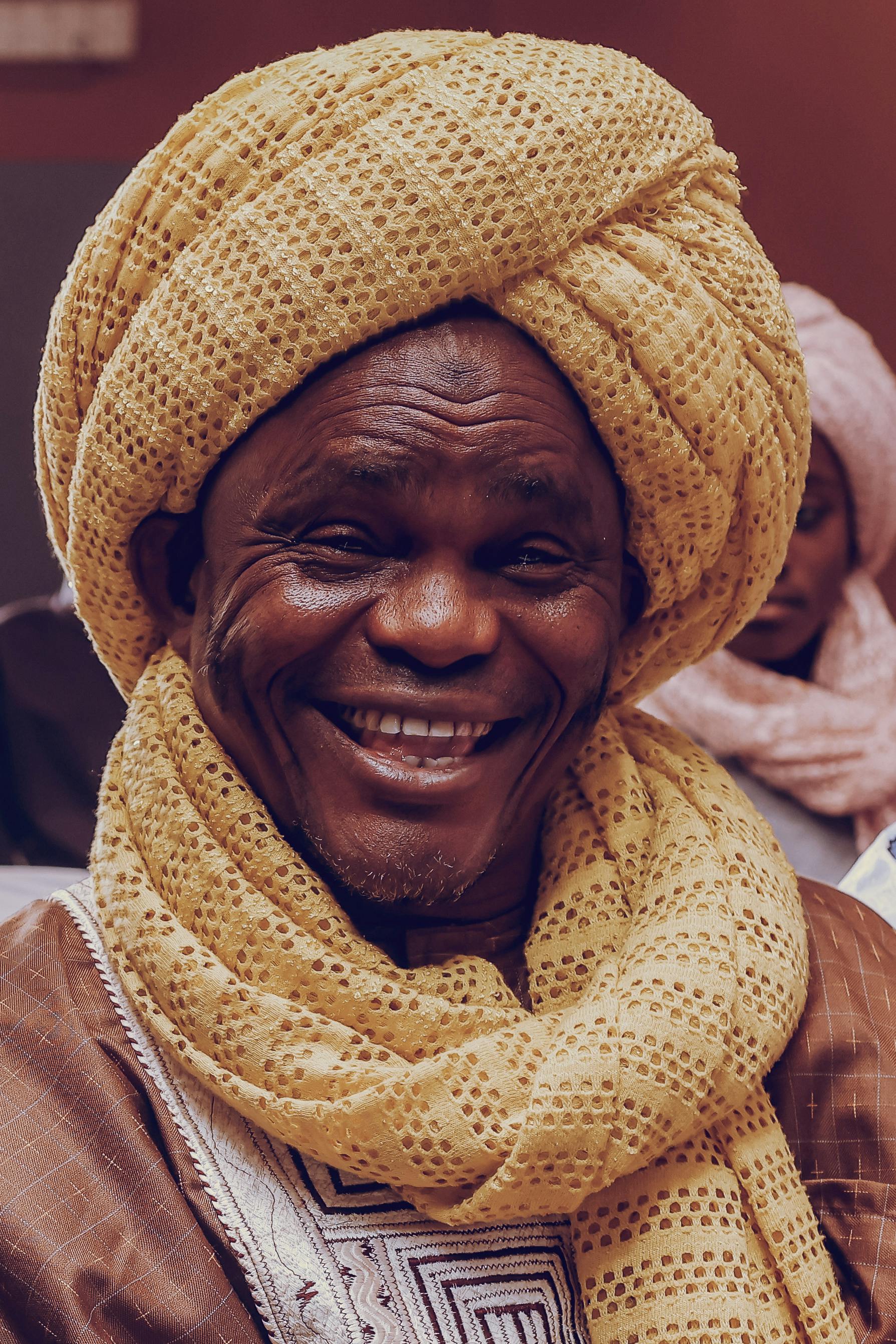 Smiling elderly man in traditional clothing with a turban, portraying warmth and culture.