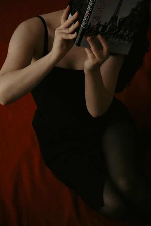 Free Elegant portrait of a woman reading in Paris, capturing a moody and artistic atmosphere. Stock Photo
