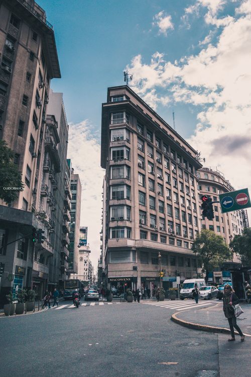 Free Street scene featuring historical architecture in a bustling city with people and traffic. Stock Photo