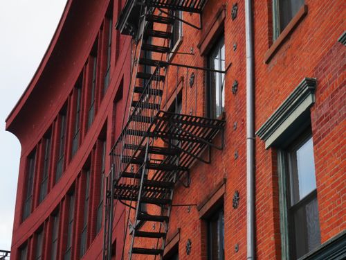 Free Close-up of a red brick building facade in New York with prominent fire escape stairs. Stock Photo