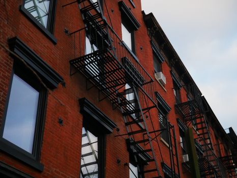 A detailed view of a red brick building with classic fire escapes in New York City.