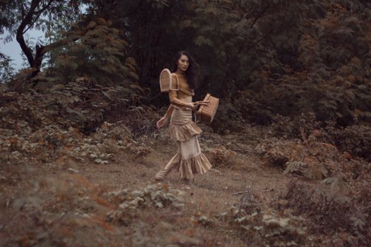 一位穿着复古服装的女人提着篮子，走过秋天的森林