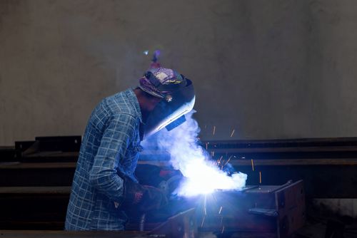 Free A welder in protective gear working with sparks in an industrial factory environment. Stock Photo
