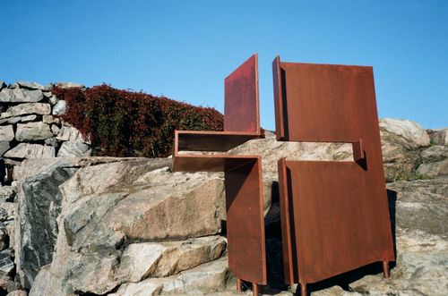 Free Abstract metal sculpture set against a rocky landscape under clear blue skies. Stock Photo