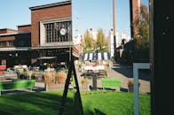 充满活力的城市景观中，现代建筑、历史建筑和绿色长凳都映照在镜面里