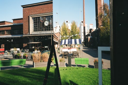 充满活力的城市景观中，现代建筑、历史建筑和绿色长凳都映照在镜面里