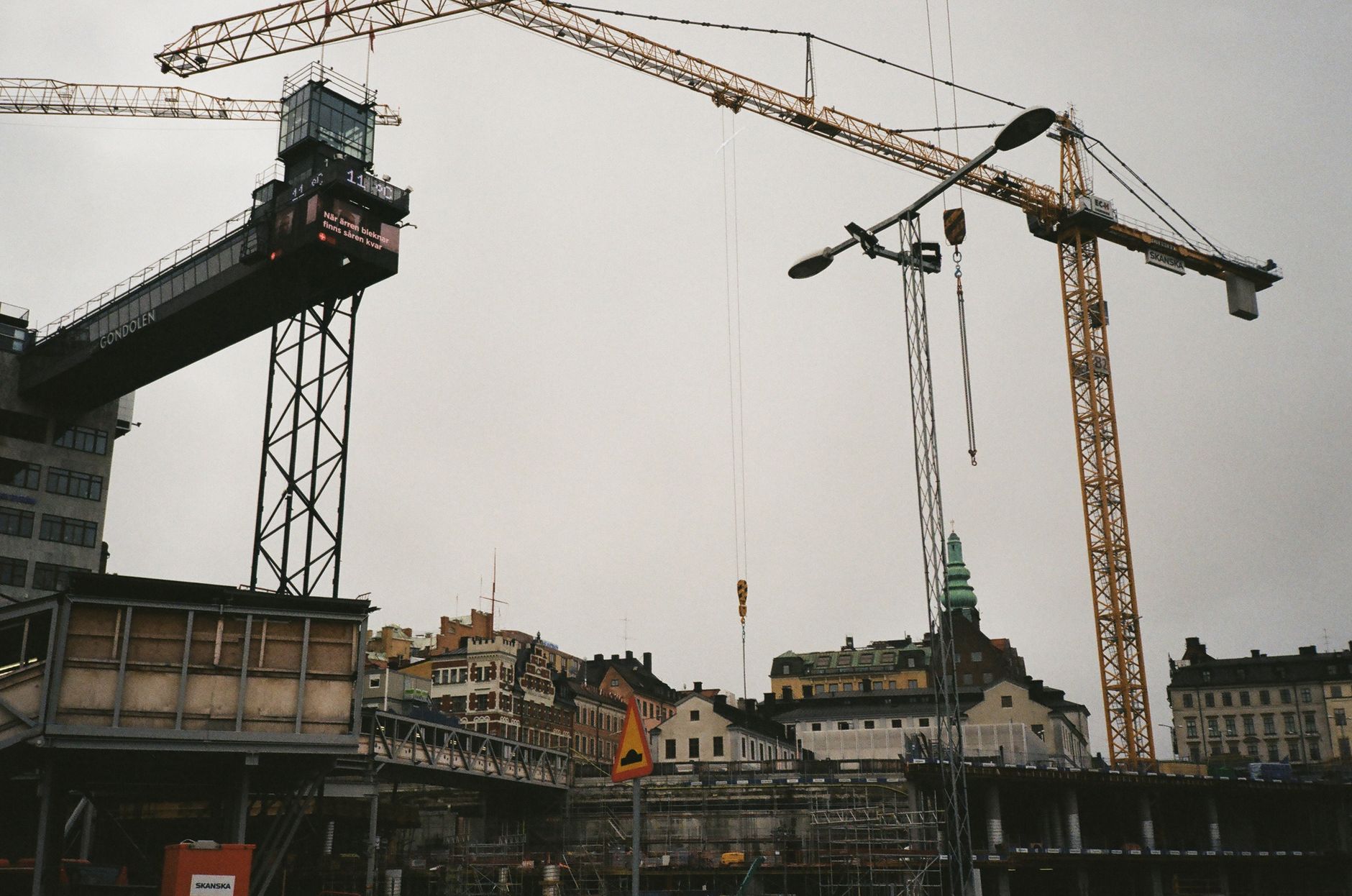 View of urban construction site with cranes and cityscape buildings.