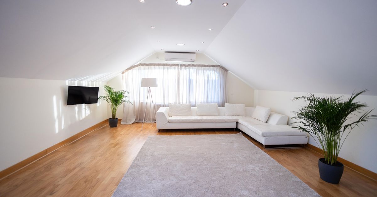 Spacious attic living room with white sofa, hardwood floor, and modern decor.