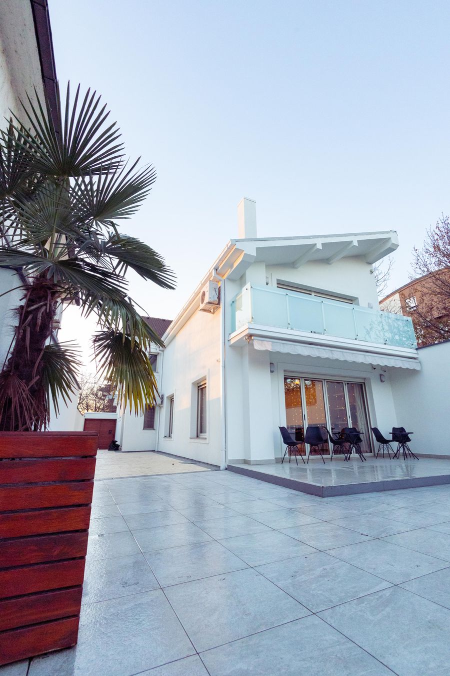 White modern house with palm trees and a covered outdoor patio