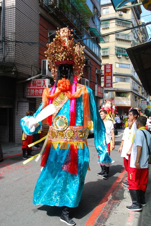 Free A vibrant Asian festival parade featuring a traditional costumed figure in an urban setting. Stock Photo