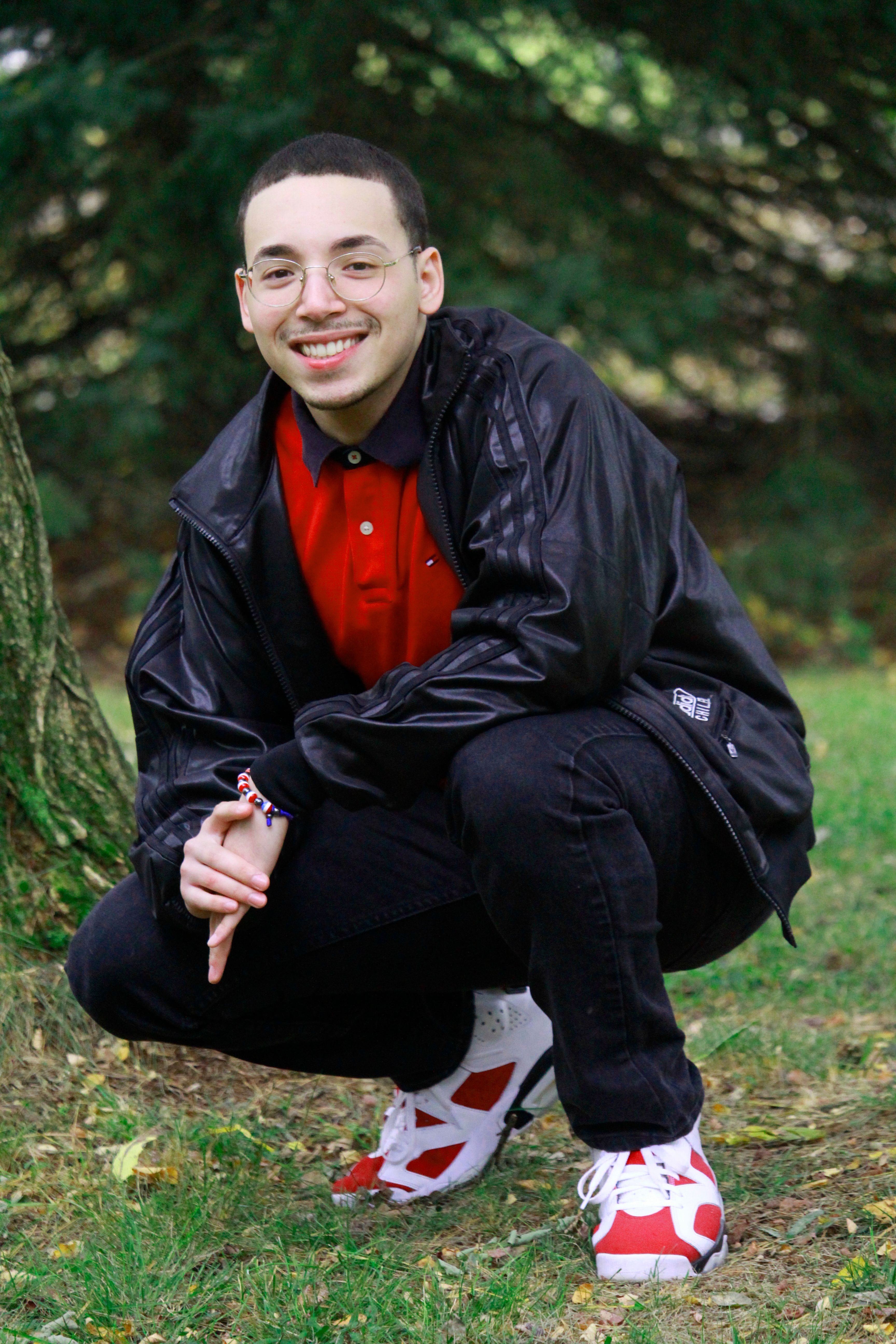 Smiling young man outdoors in a vibrant red and black casual outfit.