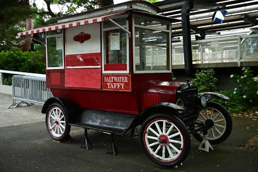 A classic red saltwater taffy cart parked in a retro amusement park setting.