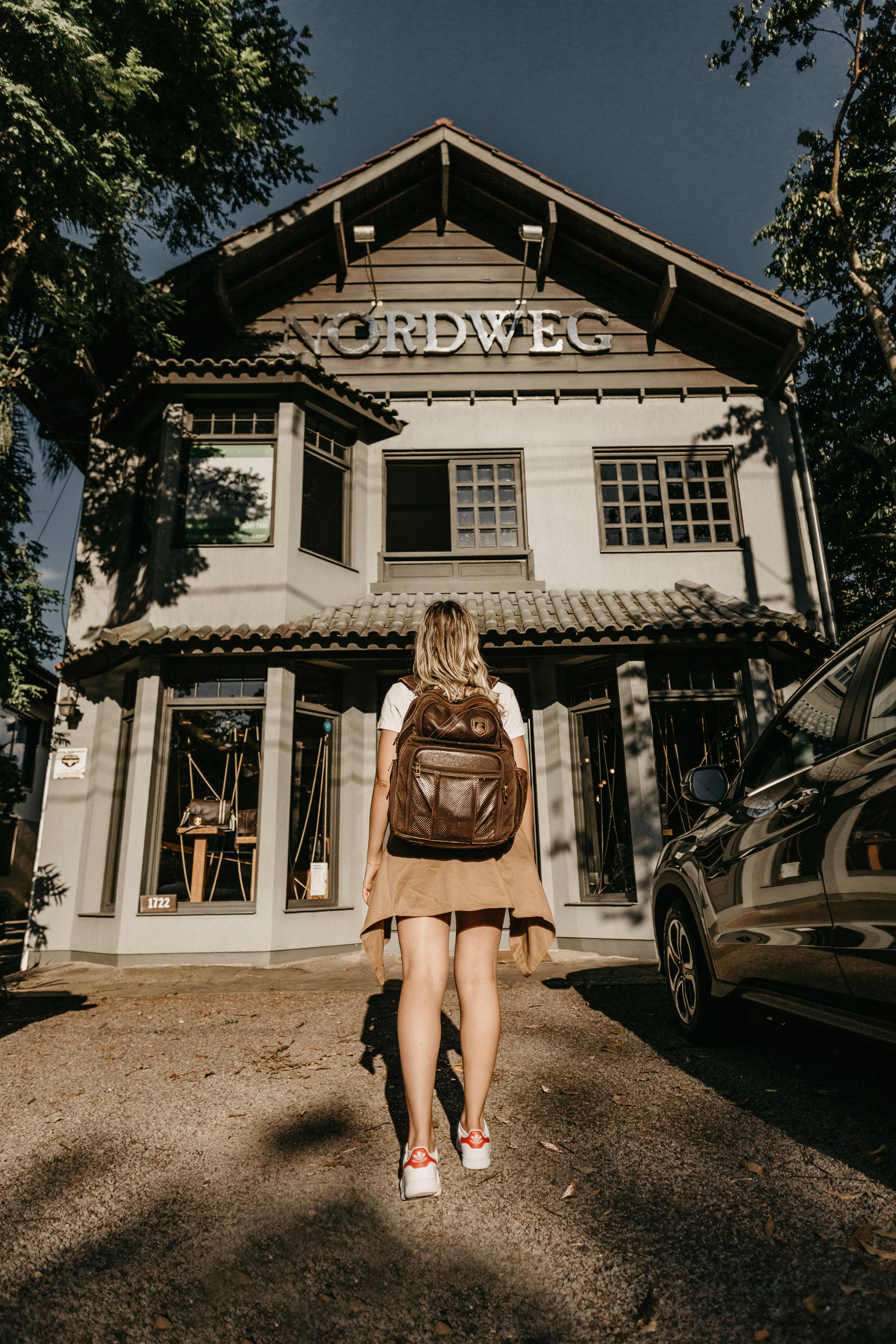一名背着背包的妇女，站在质朴的外墙前，天空晴朗