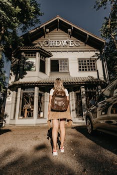 一名背着背包的妇女，站在质朴的外墙前，天空晴朗