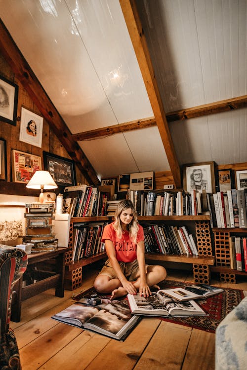 Фотография женщины, сидящей возле книжных полок