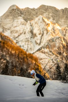 A cross-country skier in snowy Planica, Slovenia, with majestic Alpine backdrop.