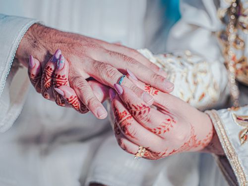Free Close-up of a bride and groom's hands with henna designs holding each other at a wedding ceremony. Stock Photo