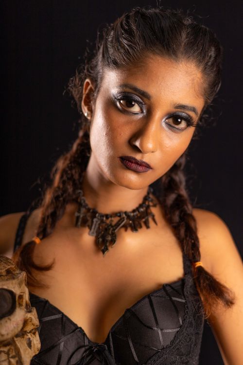 Free Close-up portrait of a woman with dramatic makeup, braids, and elaborate jewelry set against a dark background. Stock Photo