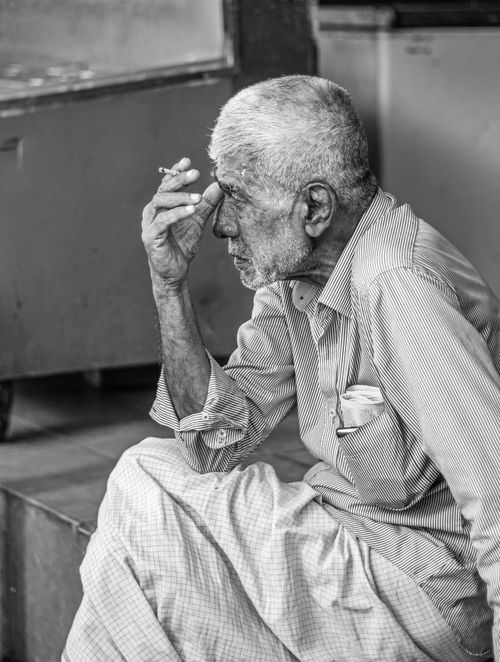 Free Black and white portrait of an elderly man sitting thoughtfully with hand on forehead. Stock Photo