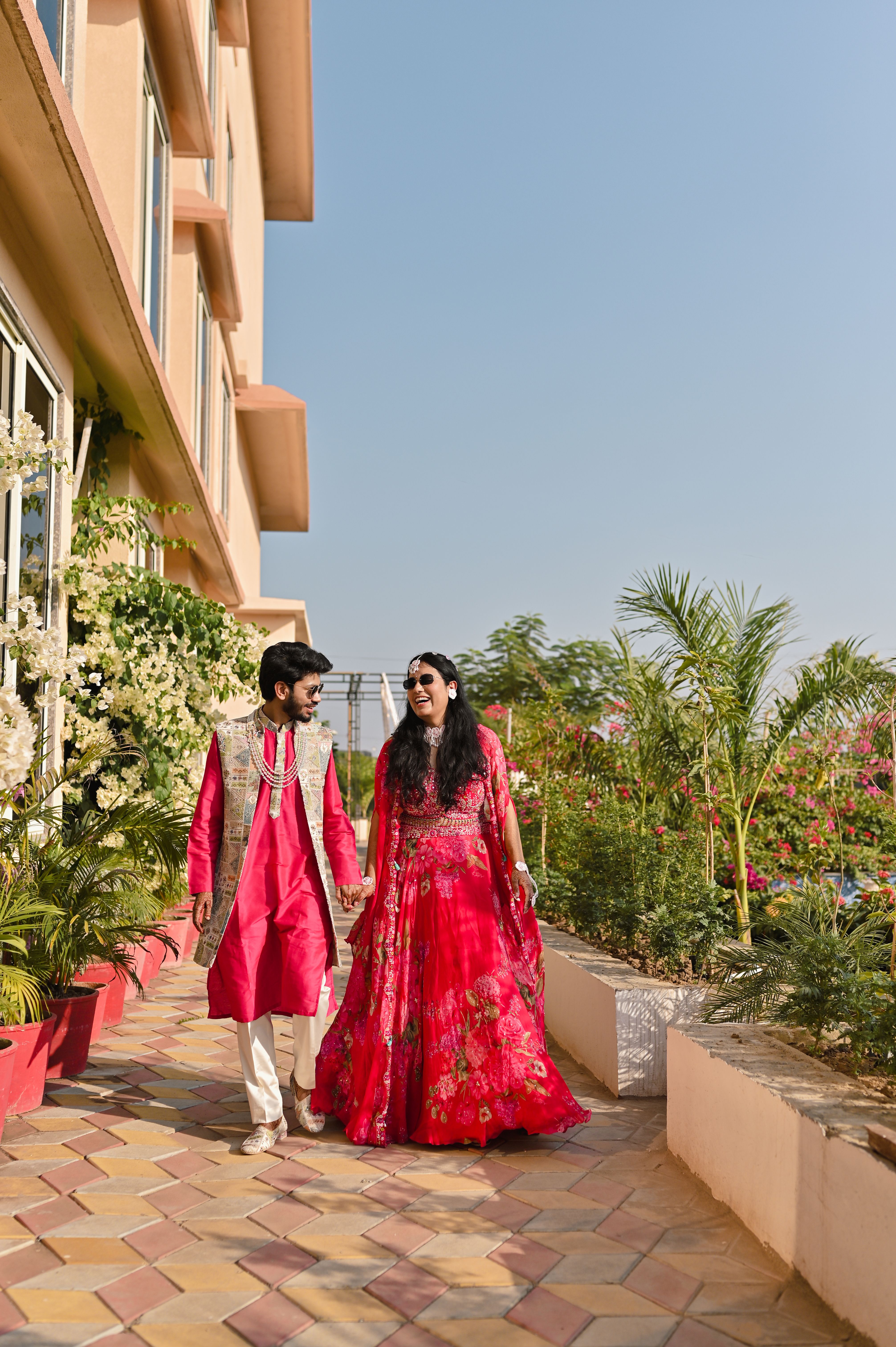 A happy couple walking in traditional Indian clothing, enjoying a sunny day.