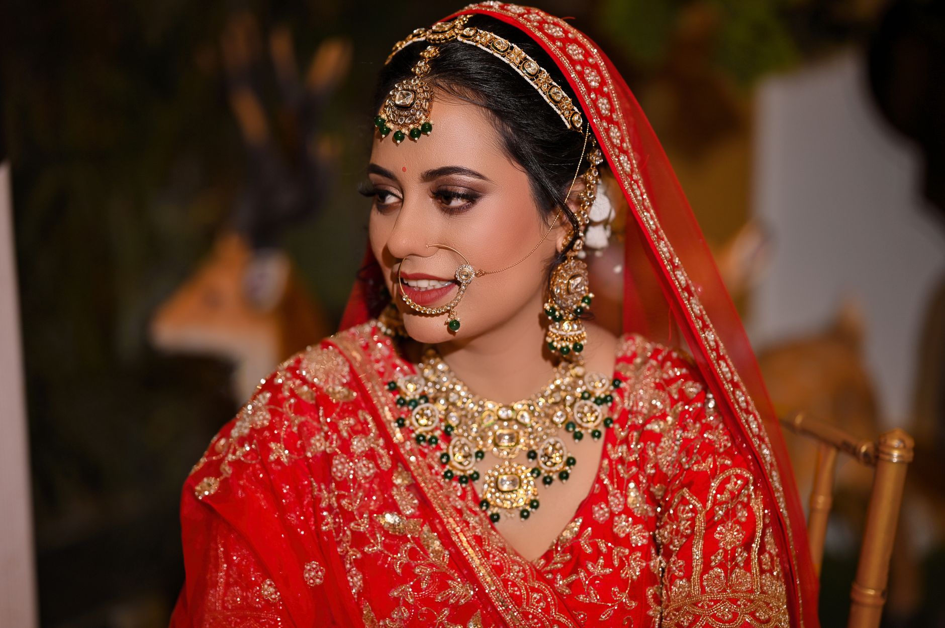 Bride in stunning red traditional wedding attire with elegant jewelry and intricate embroidery.