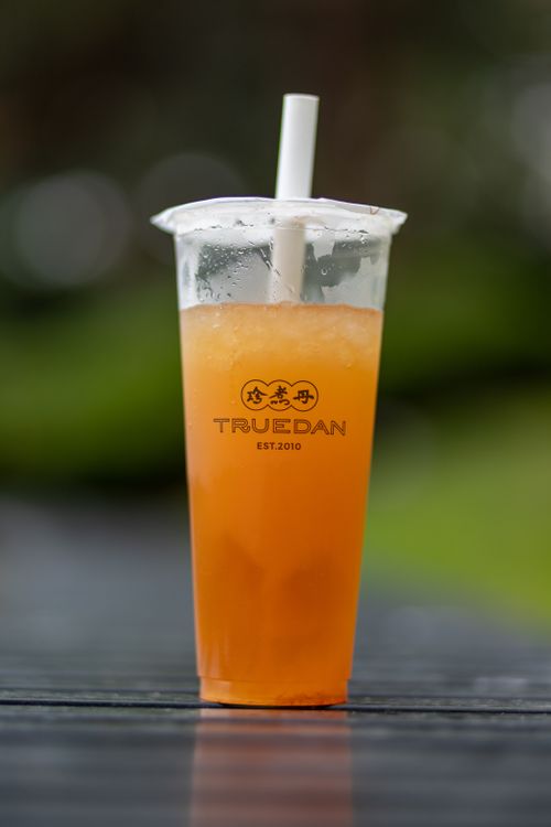 Free Chilled bubble tea in a clear plastic cup with a straw against a blurred background. Stock Photo