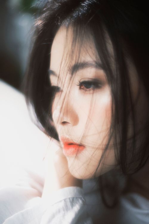 Free A serene portrait capturing a young woman lost in thought with soft lighting. Stock Photo