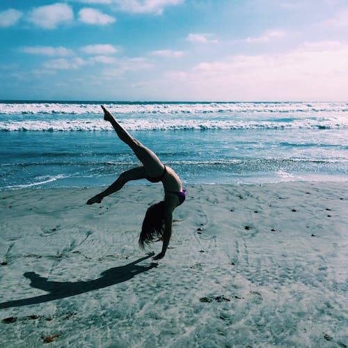 Woman Doing Handstand on Sand Beach