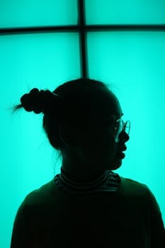 室内青色背光凸显出戴眼镜女人的艺术轮廓