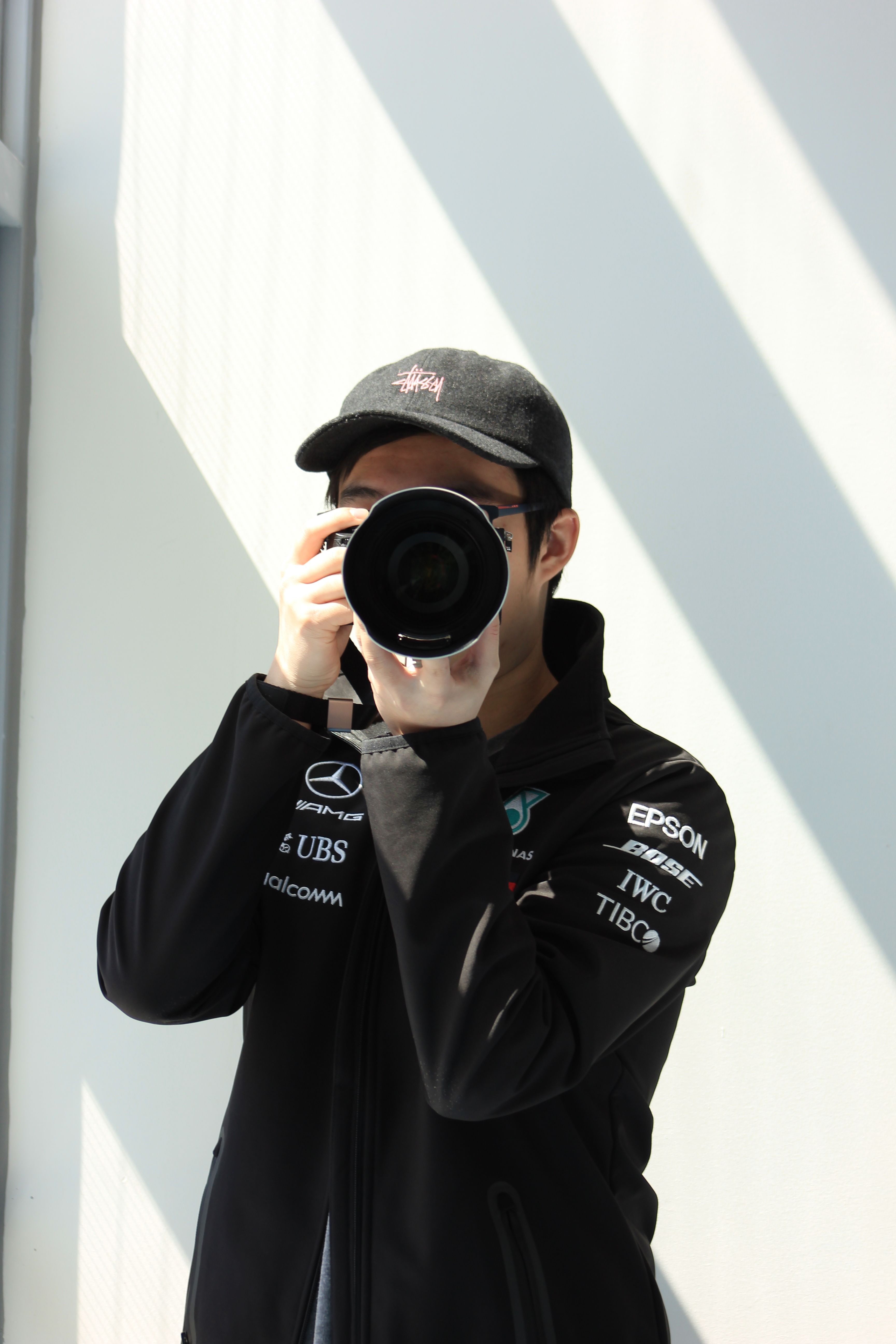 Man with camera takes a photo, bathed in bright sunlight indoors.