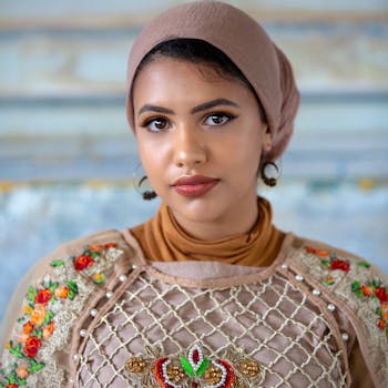 这是一幅女子肖像，她身穿彩色刺绣服装，头戴头巾，佩戴耳环，正直视着镜头