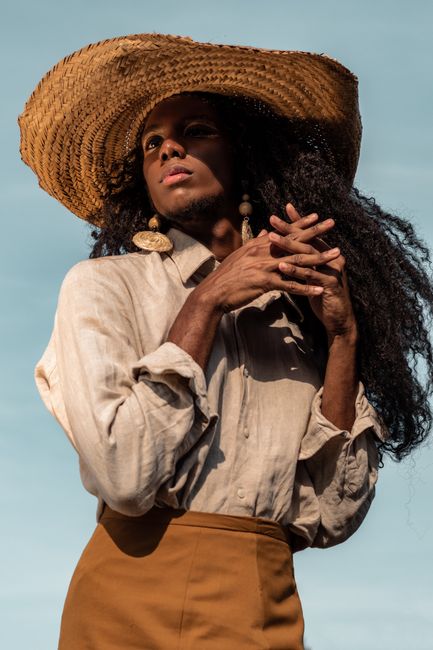 Chic portrait of a woman wearing a straw hat and fashionable outfit, exuding elegance in natural light.