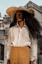 一位留着长发、戴着草帽的优雅女子，在里约热内卢的户外自信地摆着姿势